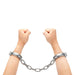 Hands wearing silver heavy-duty linked handcuffs against a white background.