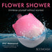 Pink and white rose-shaped waterproof stimulator partially submerged in water with water droplets on its surface.