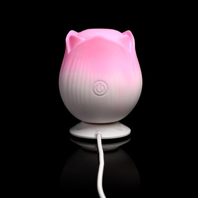 Pink and white rose-shaped pulsing stimulator with power button and charging cable on black background