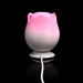 Pink and white rose-shaped pulsing stimulator with power button and charging cable on black background