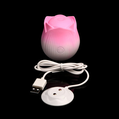 Pink rose-shaped pulsing stimulator with power button and white USB charging cable on black background.