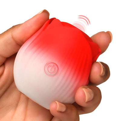 Hand holding a small red and white rose-shaped pulsing stimulator with a power button on the front.