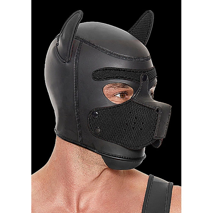 Black neoprene puppy play hood with detachable muzzle and ears, worn by a person against a black background.