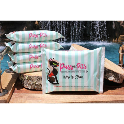 Puss and Pits premium feminine wipes 15-pack with aloe and cucumber extract displayed by a pool and waterfall.