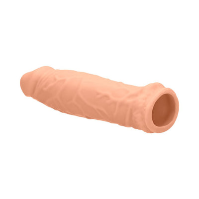 Vanilla-colored realistic penis extender sleeve with textured surface and open base design.
