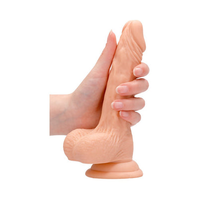 Hand holding a 7-inch vanilla-colored realistic dildo with detailed texture and suction cup base.