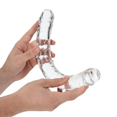 Hands holding a clear, flexible double-ended dildo with realistic detailing and a curved shape.