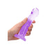Hand holding a translucent purple non-realistic dildo with suction cup base against a white background.