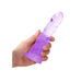 Hand holding a 7-inch purple crystal clear non-realistic dildo with suction cup base on white background.