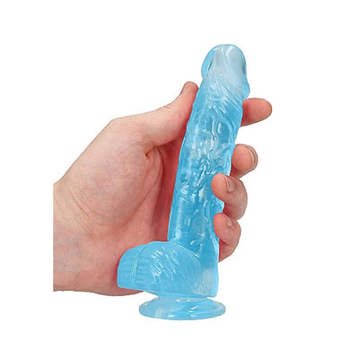 Hand holding a blue crystal clear realistic dildo with suction base and textured details.