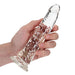 Hand holding a clear, textured 7-inch slim dildo with suction cup base against a white background.