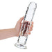 Hand holding a clear, straight 11-inch dildo with suction cup base, made from smooth, transparent material.
