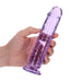Hand holding a 7-inch crystal clear purple dildo with suction cup base against a white background.