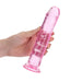 Hand holding a pink crystal clear straight dildo with suction cup base on white background