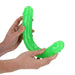 Hands holding a flexible neon green glow-in-the-dark double-ended dildo with realistic detailing.