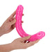 Hands holding a bright pink, flexible double-ended dildo with realistic texture and glow-in-the-dark material.