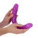 Hands holding a flexible, neon purple double-ended dildo with realistic texture and shape.