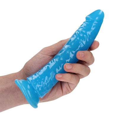 Hand holding a slim, blue, glow-in-the-dark dildo with suction cup base against a white background.