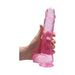 Hand holding a 9-inch translucent pink realistic dildo with suction cup base and textured details.