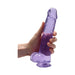 Hand holding a translucent purple realistic dildo with suction cup base and detailed texture.