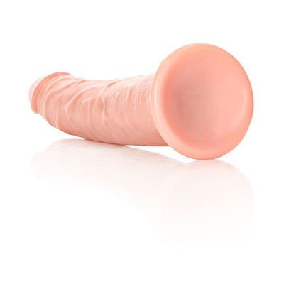 Vanilla-colored slim realistic dildo with suction cup base lying on reflective surface.