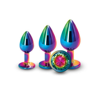 Three graduated rainbow-colored metallic trainer plugs with a jeweled base displayed on a white background.