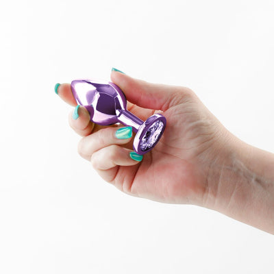 Hand holding a medium-sized purple chrome-plated metal anal plug with a jeweled base.