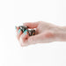 Hand holding a petite gunmetal metal anal plug with a rainbow gem base against a white background.