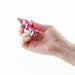 Hand holding a small pink chrome-plated metal anal plug with a jeweled base against a white background.