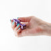 Hand holding a small, purple chrome-plated metal anal plug with a jewel base against a white background.