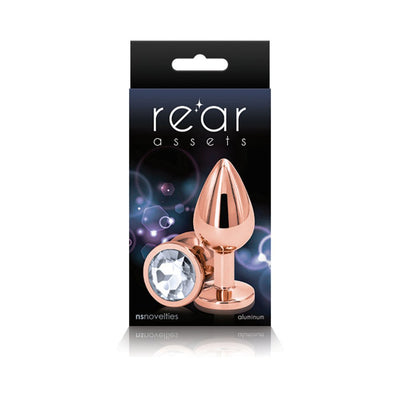 Rose gold medium-sized aluminum butt plug with a clear gem base displayed on black packaging with Rear Assets branding.
