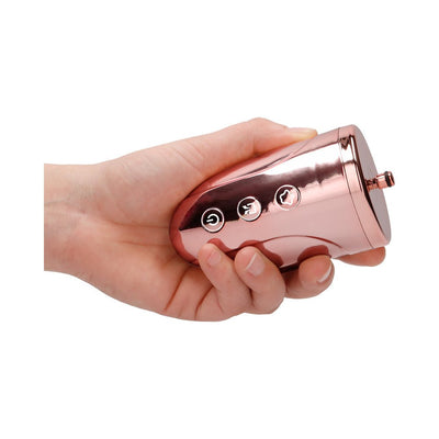 Hand holding a sleek rose gold rechargeable pump with three control buttons on the side.