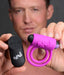 Man holding a pink vibrating cock ring with dual rings and a black remote control, both branded Bang!