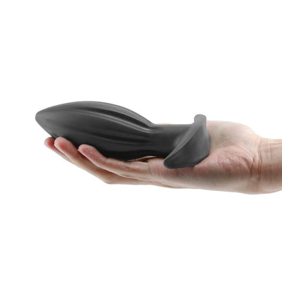 Hand holding a black silicone Renegade Bomba anal plug with a tapered, ribbed design and flared base.