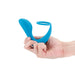 Hand holding a teal silicone dual-stimulation slingshot toy with ergonomic curves and a ring design.