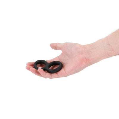 Hand holding a black Renegade Twofold stretchy silicone ring with two connected loops on a white background.