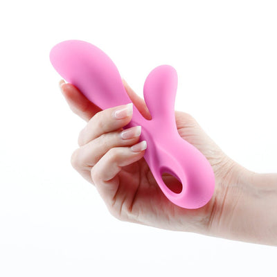 Hand holding a pink silicone dual stimulator with ergonomic design and finger loop handle.