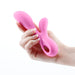 Hand holding a pink silicone dual stimulator with ergonomic design and finger loop handle.