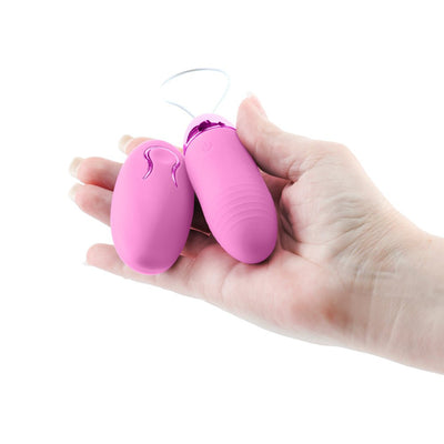 Hand holding a pink Revel Winx insertable remote bullet and wireless remote control on a white background.