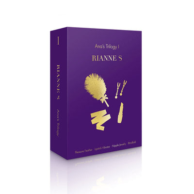 Purple box packaging of Rianne S Ana's Trilogy Set 1 featuring gold illustrations of a feather, lipstick vibrator, nipple jewelry, and blindfold.