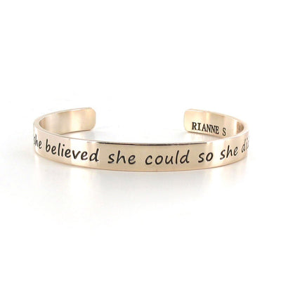 Gold-tone open cuff bracelet with engraved inspirational quote and Rianne S branding inside.