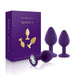 Set of three purple silicone booty plugs with jeweled bases displayed next to elegant purple and gold packaging box.