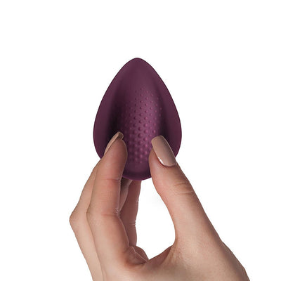 Hand holding a burgundy teardrop-shaped textured silicone pleasure device with a smooth matte finish.