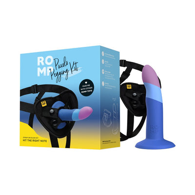 Romp Piccolo Pegging Kit with adjustable black harness and blue and purple silicone dildo next to product packaging.
