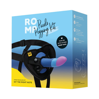 Packaging of Romp Piccolo Pegging Kit featuring a blue and pink silicone dildo with adjustable black harness on a blue and yellow background.