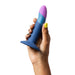 Hand holding a small, curved silicone dildo in blue and purple with a flared base and ROMP logo.