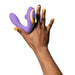 Hand holding a purple ROMP Reverb dual stimulator with yellow accents against a white background.