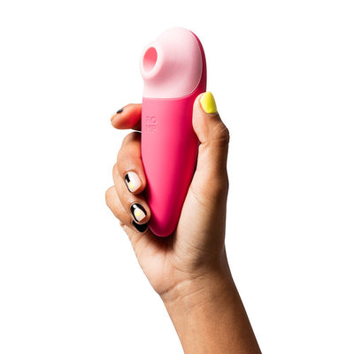 Hand holding a pink and light pink ROMP Shine X silicone pleasure device with a smooth, ergonomic design.