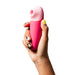 Hand holding a pink and light pink ROMP Shine X silicone pleasure device with a smooth, ergonomic design.