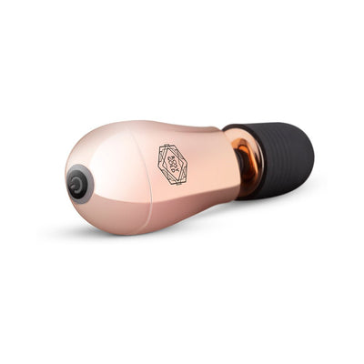 Compact rosy gold mini massager with soft black silicone head and single button control on white background.